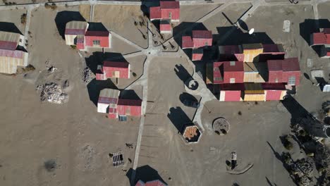 Overhead-shot-of-eco-lodge-in-the-deserted-landscape-of-Salar-de-Uyuni-and-at-the-foot-of-the-Thunupa-volcano,-Bolivia,-Mexico,-USA