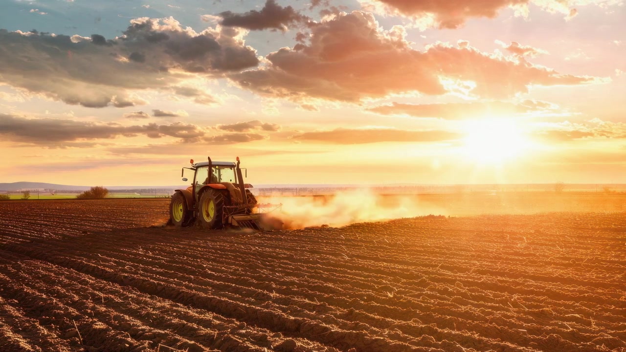 Trator Arando Campo Agrícola ao Pôr do Sol