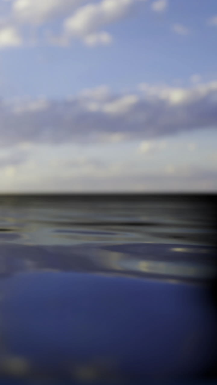 Waves and clouds by the open sea at sunset near the horizon line