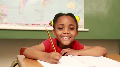 Happy-pupil-writing-in-notepad-at-desk