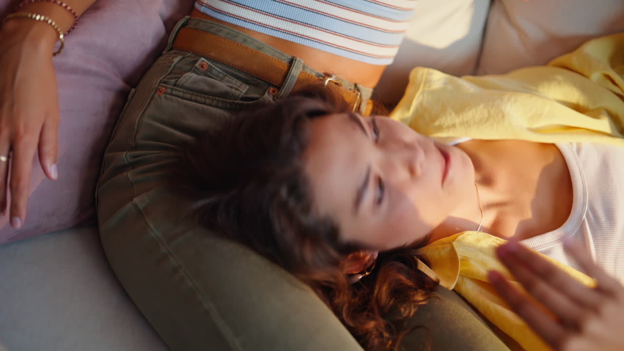 Smilende kvinde lytter til ven, mens de slapper af sammen i en sofa i en lejlighed - nærbillede