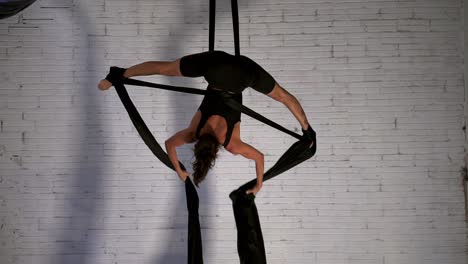 female dancer doing an aerial dance performance while hanging upside down, front view