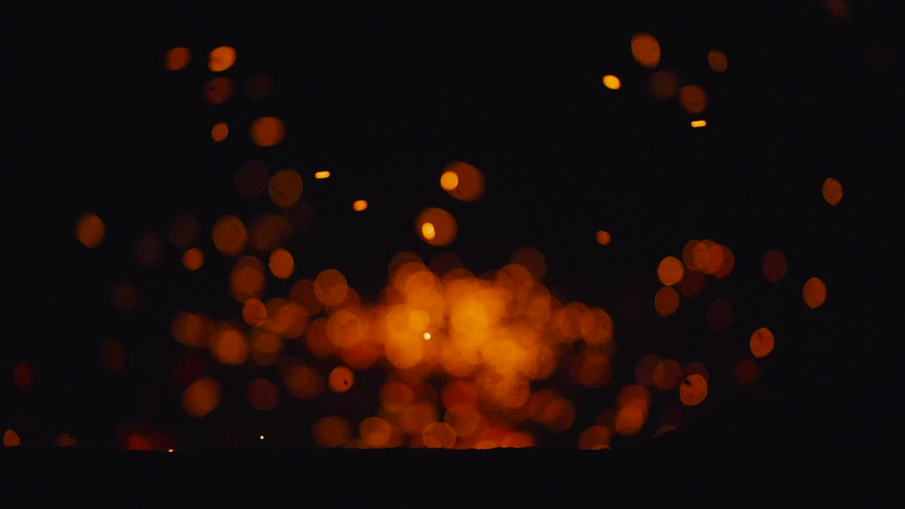 Sparks in the tank fly out of the fire on a black background