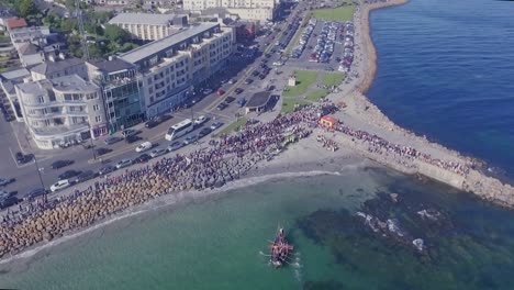 Toma-Aérea-De-Vikingos-Remando-Y-Aterrizando-En-Salthill-Beach,-Galway,-De-Arriba-Hacia-Abajo