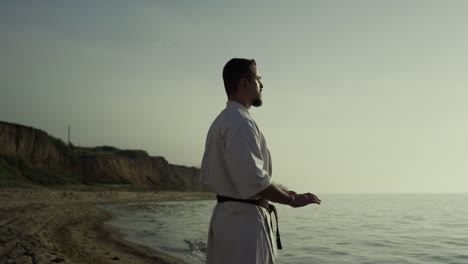 Sportler-Macht-Meditationsübungen-Am-Strand.-Karate-Kämpfer-Perfektioniert-Seine-Technik