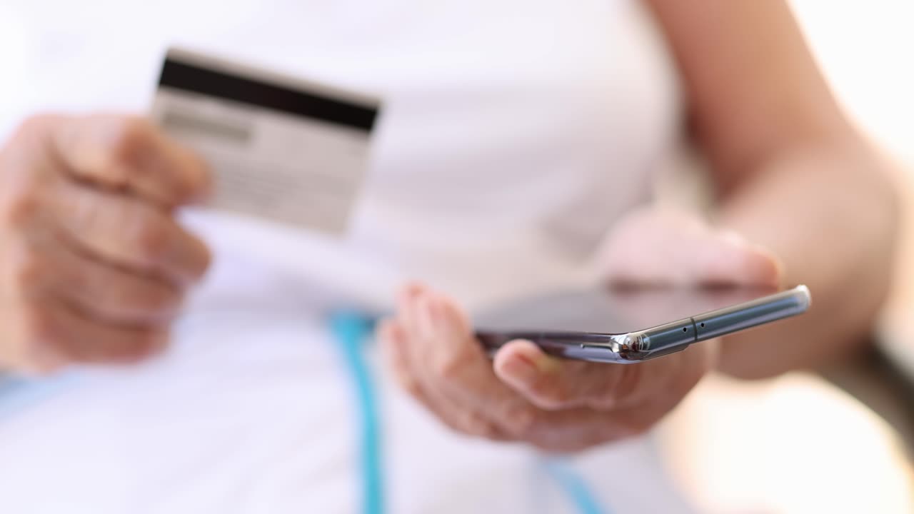 Donna che usa il telefono cellulare e la carta di credito per il pagamento online