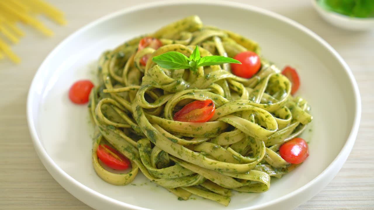 espaguetis fettuccine con salsa pesto y tomates - estilo de comida vegana y vegetariana
