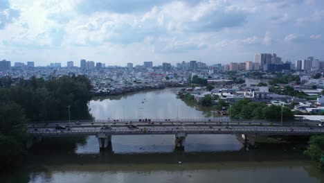 mosca aérea en toma de puente de tráfico urbano y viviendas frente al mar de alta densidad a lo largo de un canal en la ciudad de ho chi minh, vietnam en la luz de la tarde