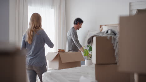 Pareja-Feliz-Mudándose-A-Una-Nueva-Casa-Colgando-Un-Cuadro-En-La-Pared-Decorando-La-Casa-Disfrutando-Del-Trabajo-En-Equipo-4k