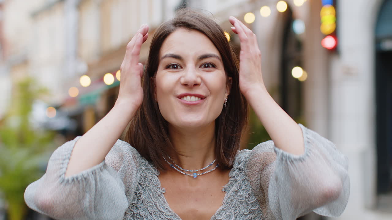 молодая женщина выглядит удивлена в камеру шокирована внезапной победой хорошие новости о победе вау на городской улице