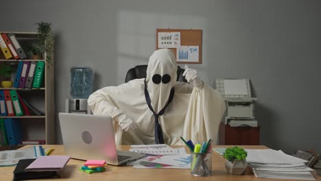 halloween businessman ghost in white sheet working at office standing and dancing in the room having