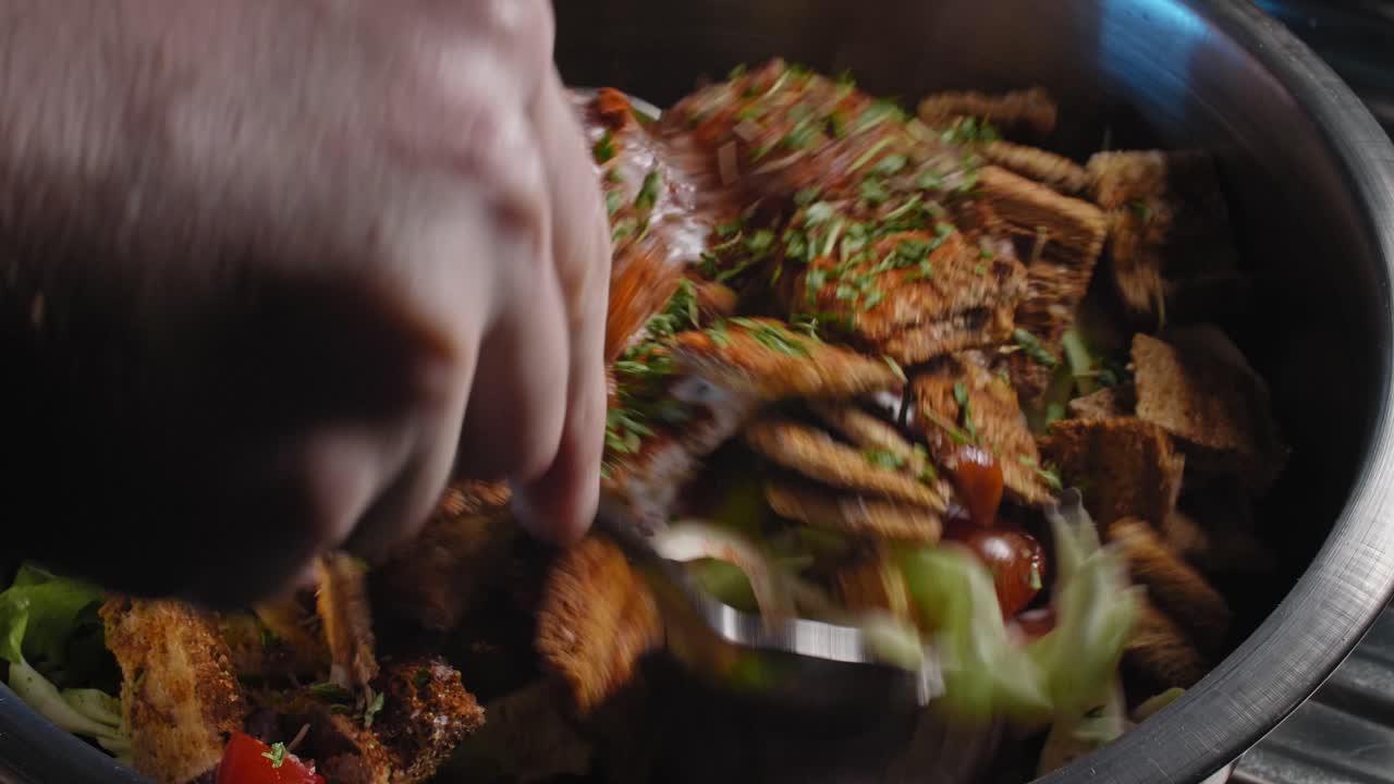 primer plano de un chef mezclando una ensalada de atún en un recipiente metálico