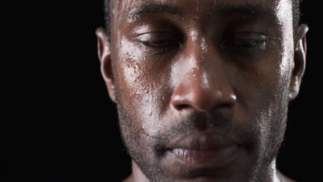 Close-up-of-an-African-American-man-athlete's-face-glistening-with-sweat-on-a-black-background