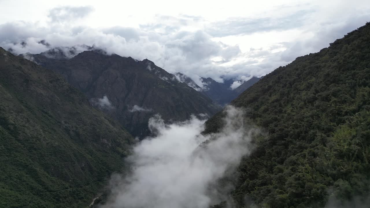 Nuvens suaves e névoa envolvem um vale andino, com um rio traçando um caminho através da neblina