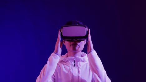 asian woman using vr headset on blue background, copy space, slow motion