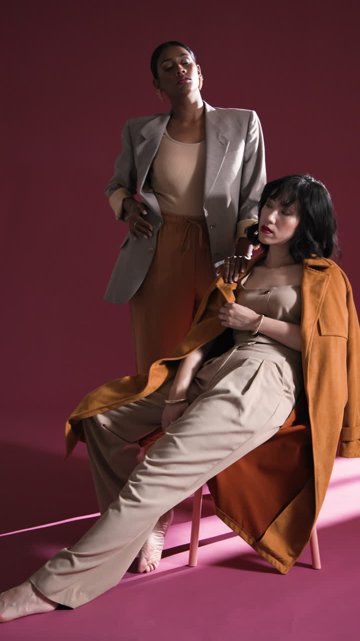 Vertical video: Confident women in stylish outfits posing in studio, showcasing modern fashion