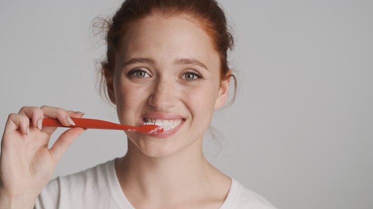 Fille rousse devant la caméra sur fond gris