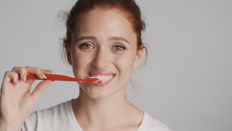 redheaded girl in front of camera on gray background.