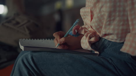 las manos de la chica escribiendo pensamientos en el cuaderno de cerca. estudiante haciendo la tarea de arte.