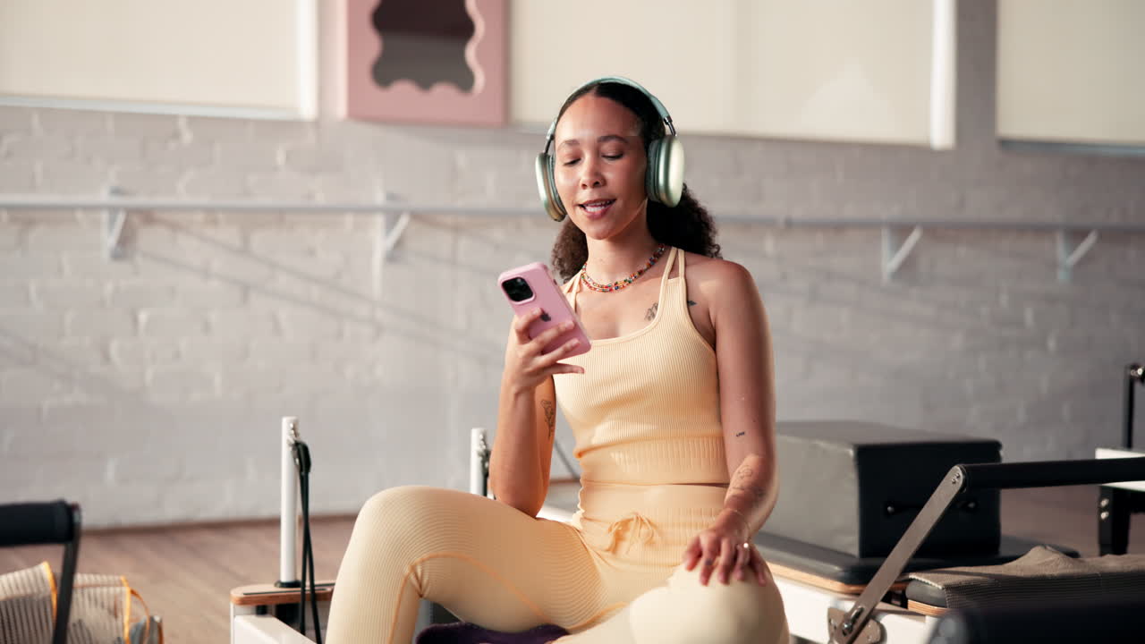 Donna che usa il telefono con le cuffie in uno studio di pilates