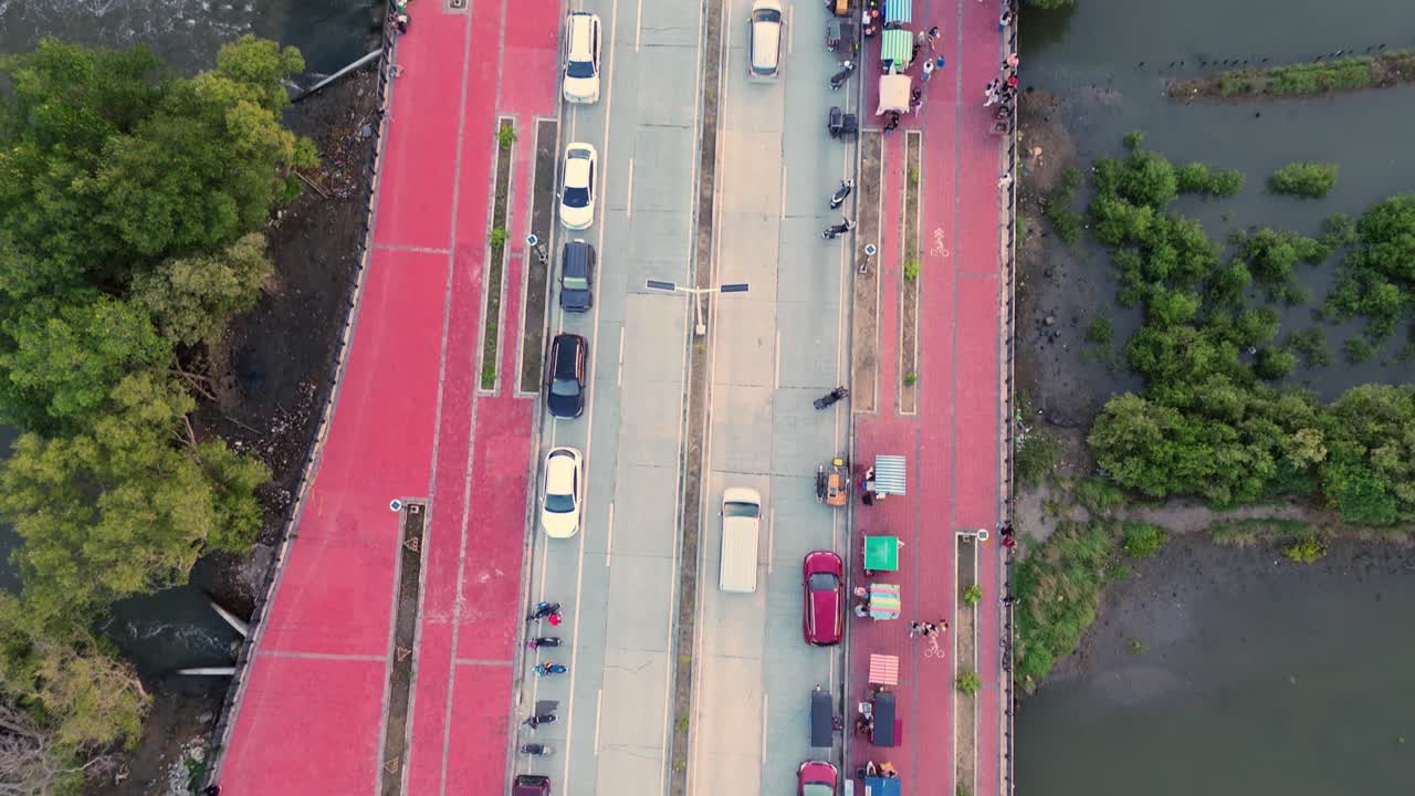 Top-down aerial of a coastal road lined with parked vehicles beside a waterfront and mangroves in the Philippines. Great for travel, urban, and transportation projects