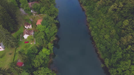 The-most-cinematic-view-of-a-river-streaming-in-the-landscape-and-a-community,-covered-with-lush-forest-and-mountains