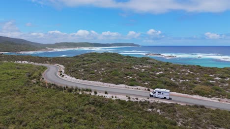 Campervan-driving-along-coastal-road-in-summer