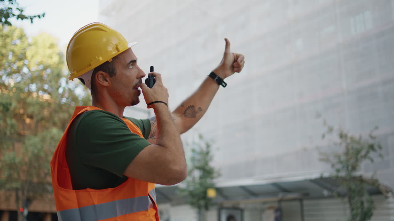 Hardhat man giving instructions using walkie-talkie in construction site closeup