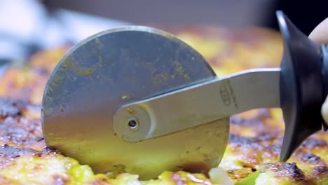 close-up-shot-of-a-pizza-cutter-cutting-delicious-tasty-home-made-gourmet-pizza