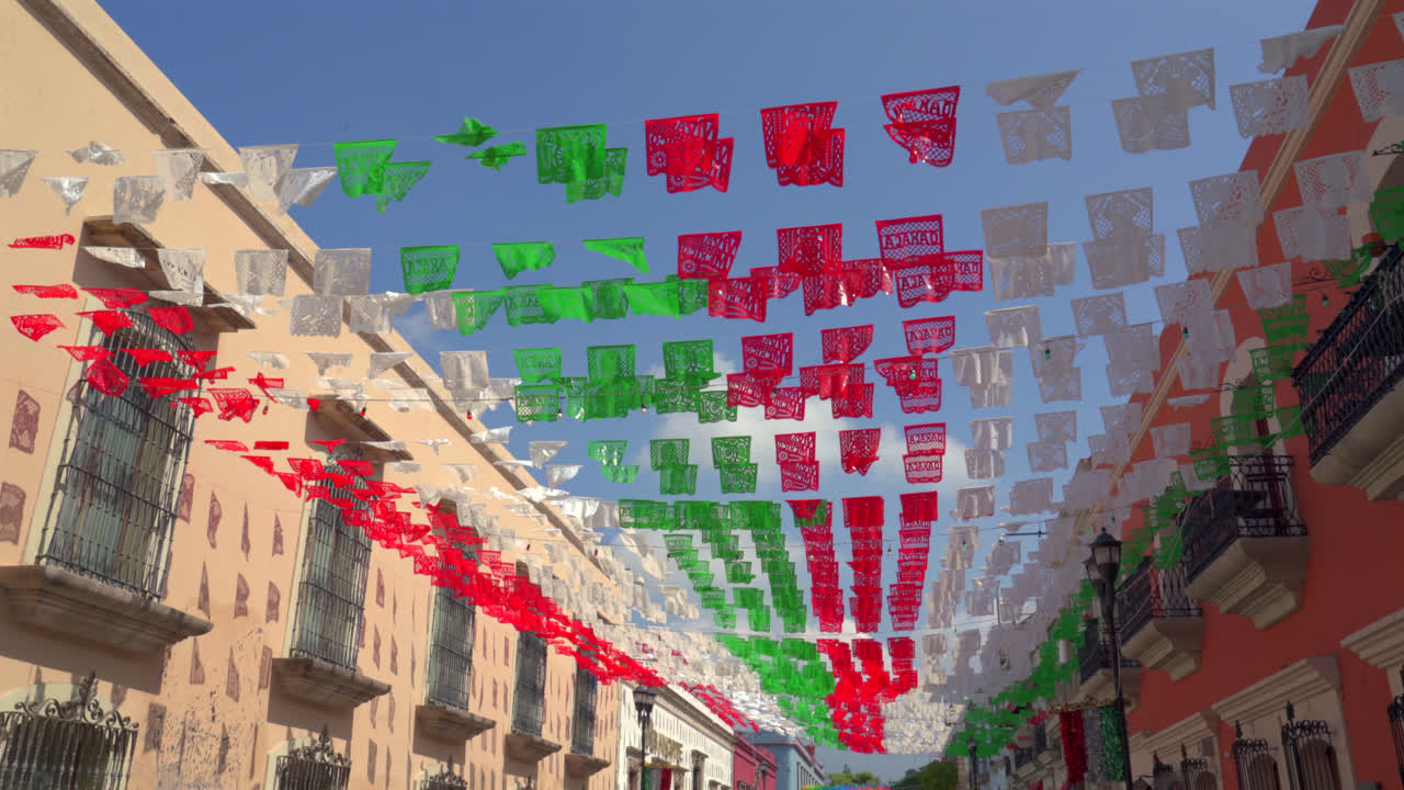 Colorful papel picado banners flutter above festive setting with bright cut-paper designs in Mexico, medium static overhead view