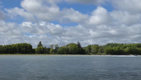 Jetboote-Fahren-An-Einem-Bewölkten-Sommertag-Flussaufwärts-Neben-Tiefgrünen-Weidenbäumen-Entlang-Des-Waimakariri-Flusses