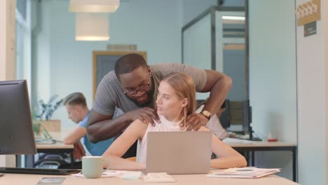 pretty woman working on computer at coworking. black man making massage