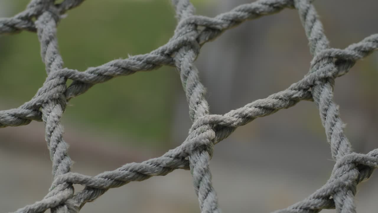 A close-up of a tightly knotted rope outdoors, highlighting texture and structure in soft light