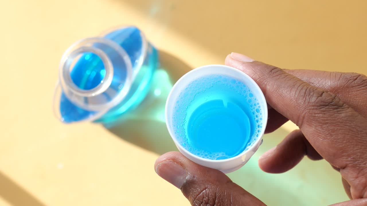 Close up of a blue cleaning product with a hand holding the cap