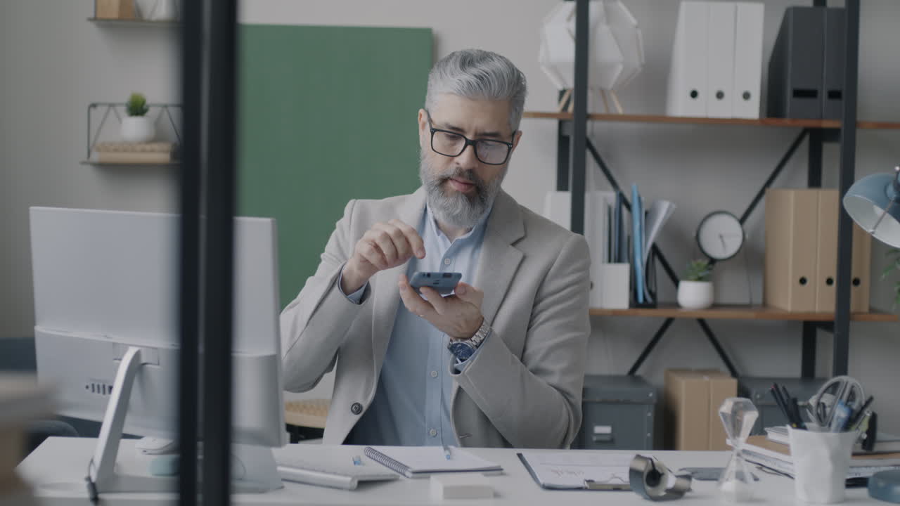 Forretningsmand arbejder på en smartphone på sit kontor