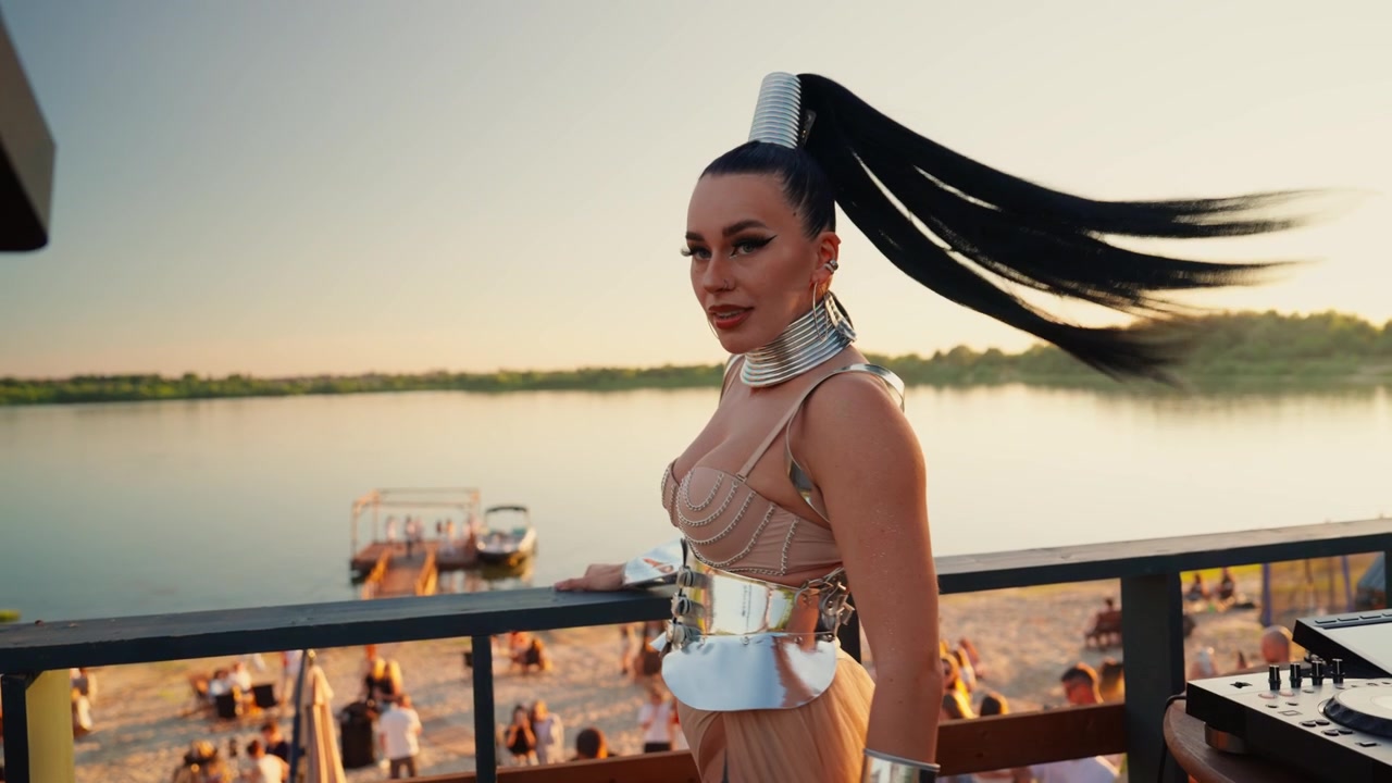 DJ donna che si esibisce a una festa in spiaggia al tramonto
