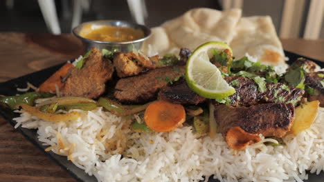 sauced fork picks up piece of beef from plated tandoori kabob dish, slow motion slider close up 4k