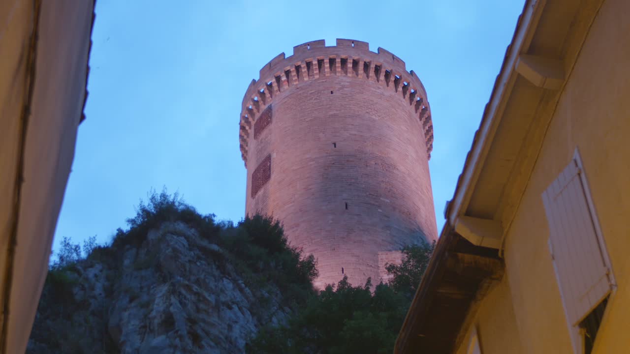 Historic medieval castle tower of Foix standing tall against blue twilight sky, symbol of heritage