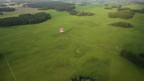 toma aérea del globo aerostático aterrizando en el campo verde de la granja