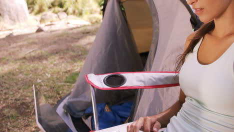 woman using a laptop outside the tent