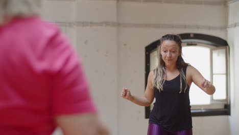 Front-view-of-female-instructor-dancing-in-front-of-group