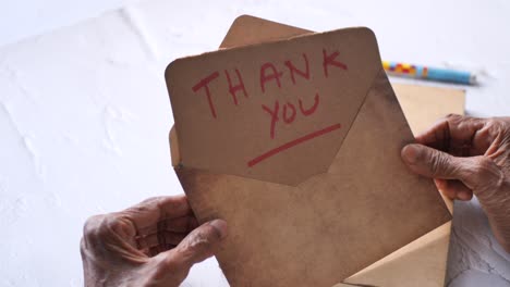 old hands holding thank you letter envelope