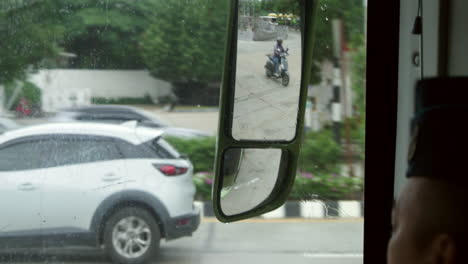 rainy day traffic view from a bus mirror in thailand