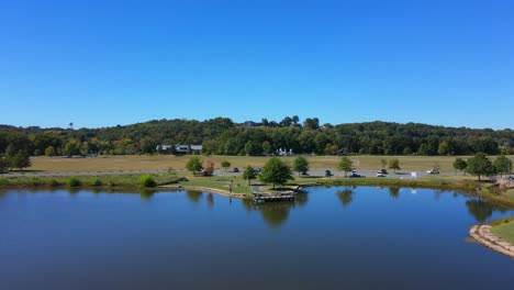 drone shot flying over the lake toward the fishing pier with some people fishing