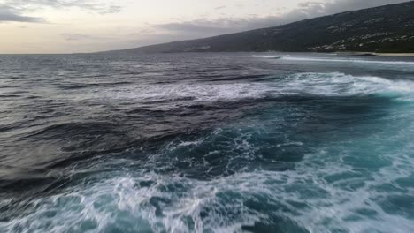 imágenes de drones de primer plano de olas rompiendo en una playa rocosa hecha de lava enfriada durante la puesta de sol