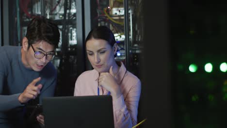 Diverse-female-and-male-it-technicians-using-laptop-checking-computer-server