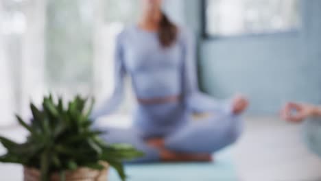 multiracial women practicing patience mudra and meditating together in yoga studio