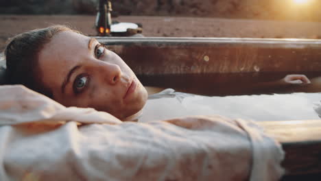 woman lying in dirty bath and posing for camera at sunset