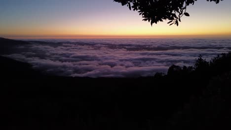 Un-Lapso-De-Tiempo-Del-Amanecer-Sobre-Las-Nubes-Desde-Una-Montaña-Debajo-De-Un-árbol