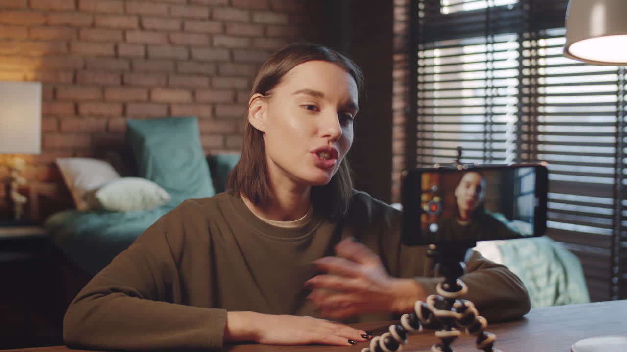 mujer alegre filmando vlog con un teléfono inteligente en un trípode